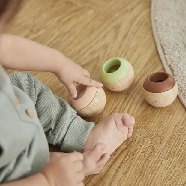 Ein Baby sitzt im Wohnzimmer und spielt mit Sensorik kugeln von plantoys