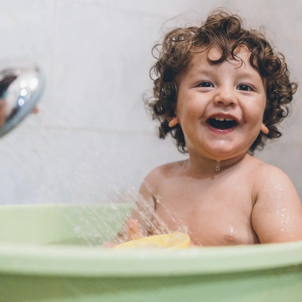 ein Kind in einer Badewanne mit Bio Pflege Produkten von Weleda