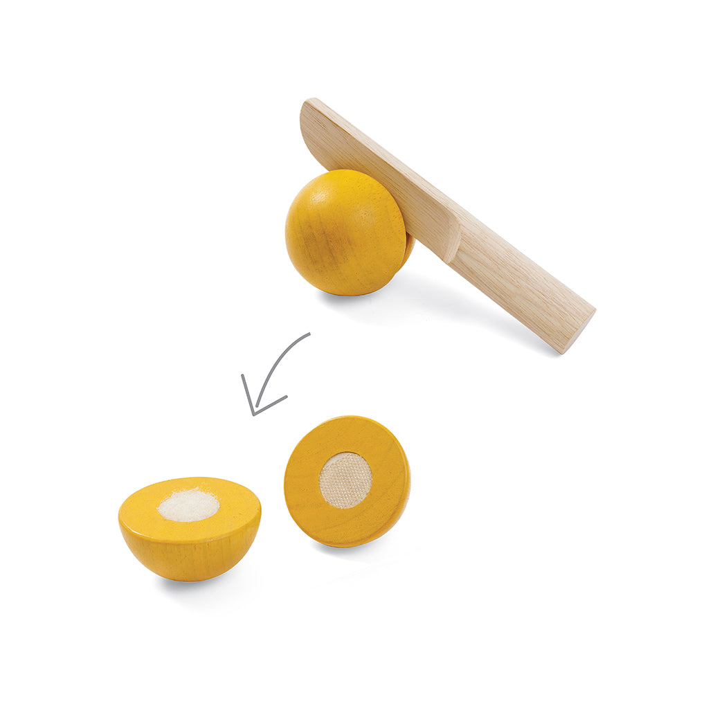Eine Zitrone aus Holz wird zerschnitten mit einem Holzmesser aus einem Holzspielzeug Set