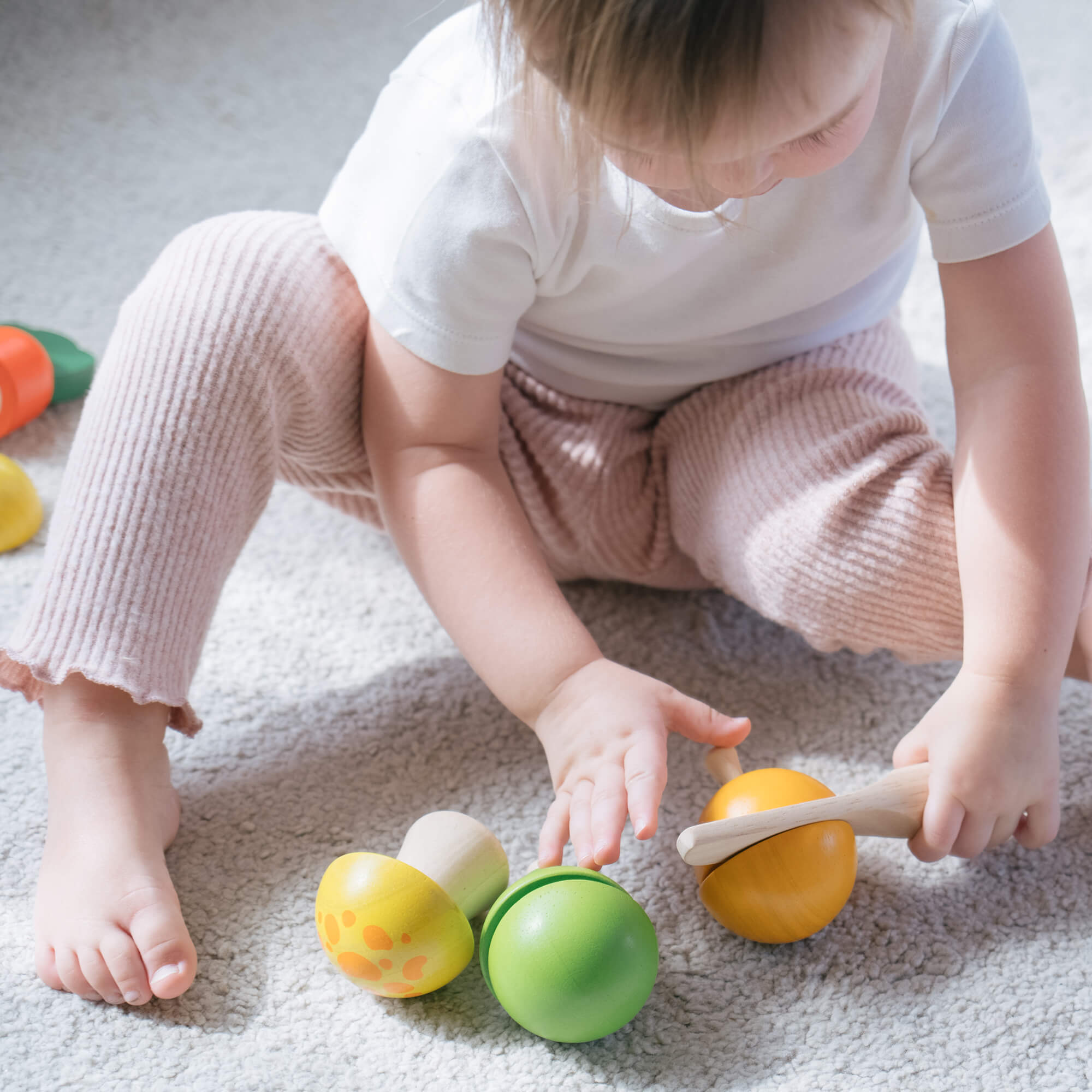Ein Baby spielt mit Holzfrüchten und schult die Motorik